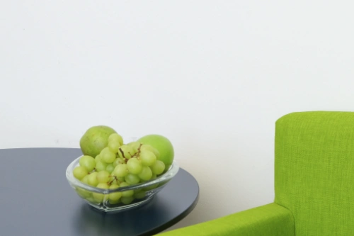 Unser Wartebereich: ein grüner Sessel und eine Obstschale mit Äpflen und Trauben.